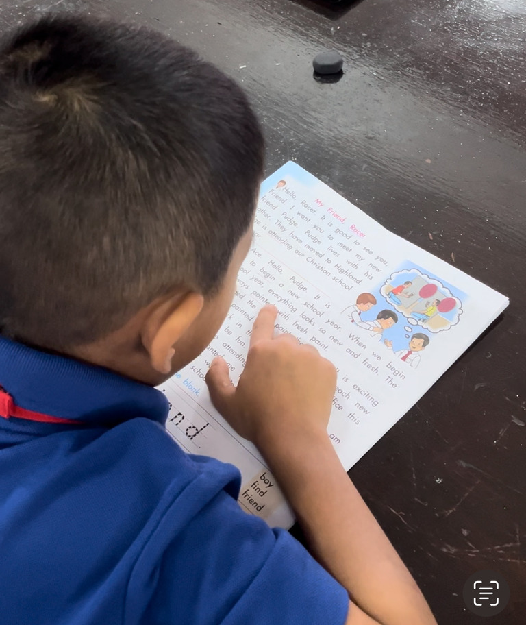 Junger Schüler liest aufmerksam ein Arbeitsblatt im Computerzentrum