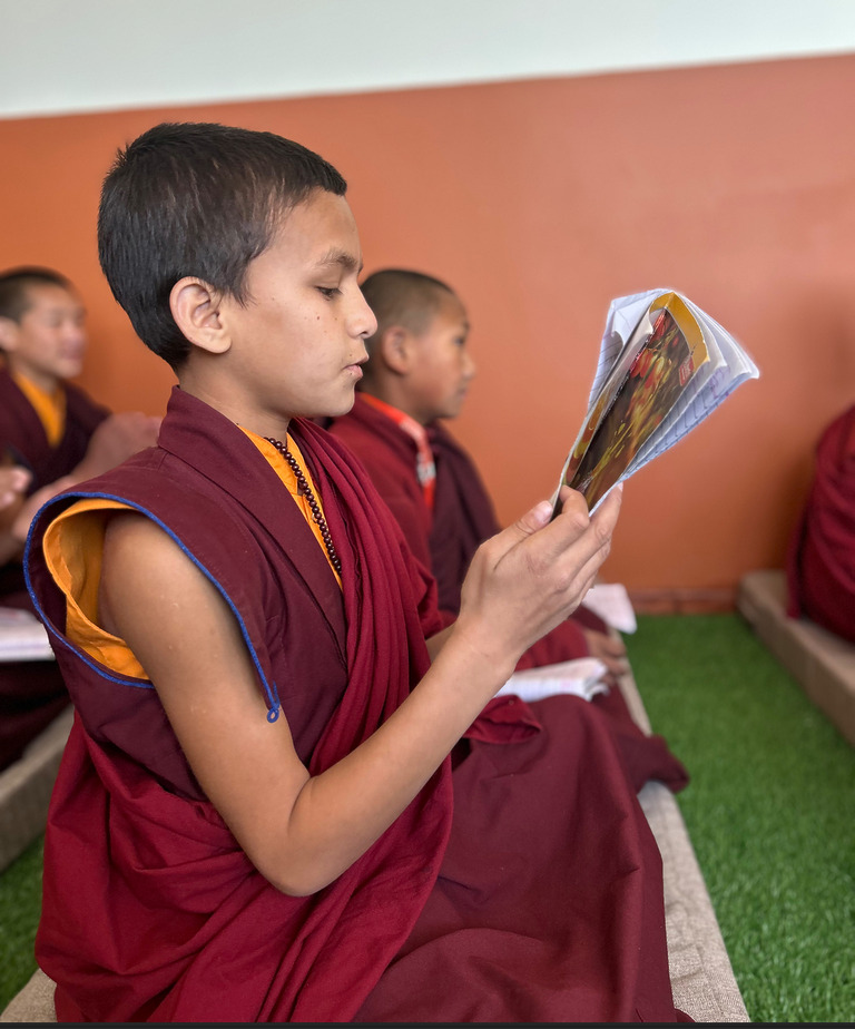 Junger Mönch liest laut aus einem religiösen Text in der Klosterschule.