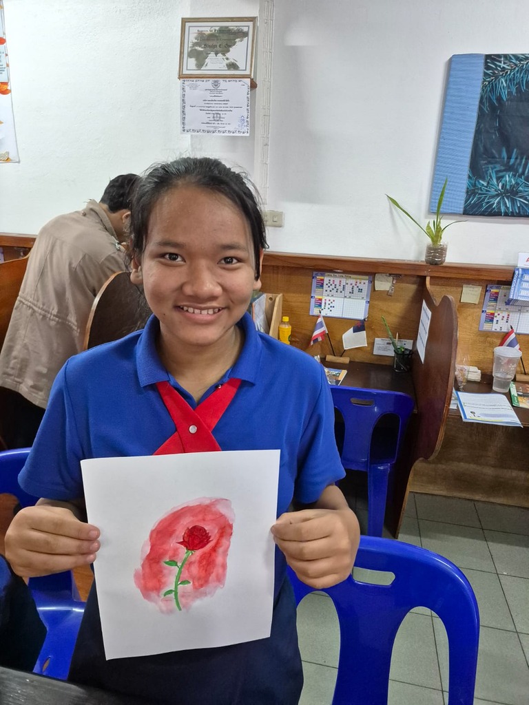 Schülerin hält stolz ein selbst gemaltes Bild im Computerzentrum hoch.