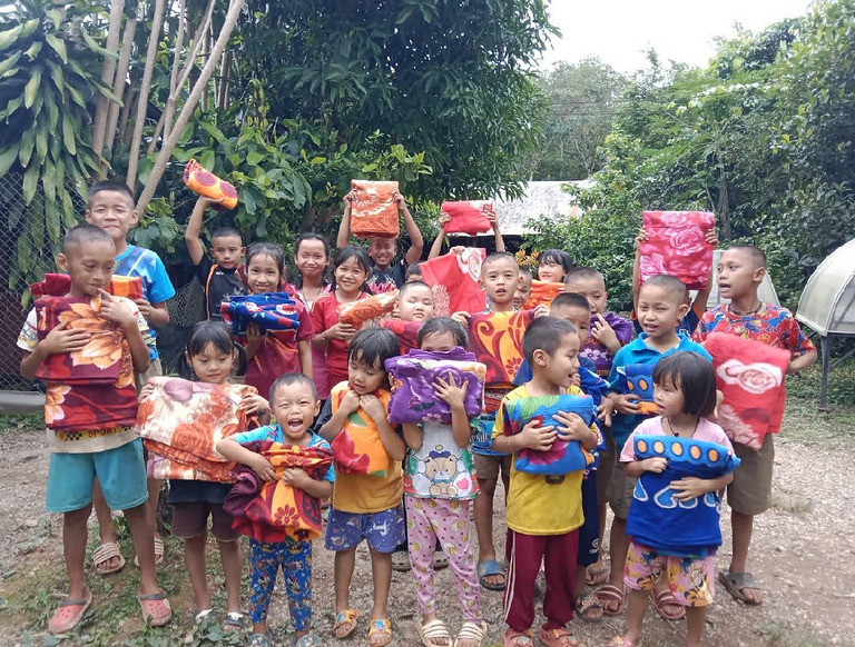 Projektteam übergibt Geschenke und Hilfspakete an Kinder in einem Dorf