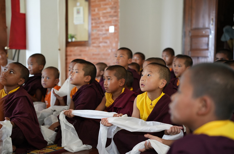 Gruppe von Mönchen in traditioneller Kleidung während des Unterrichts in der Klosterschule.