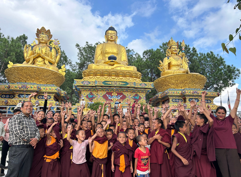 Schüler und Lehrer der Klosterschule posieren vor einer großen goldenen Buddha-Statue