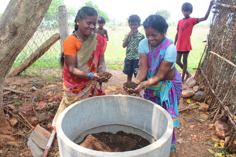 Frauen mischen organische Materialien in einem großen Behälter zur Herstellung von Kompost oder Biogas – Umweltprojekt in Tamil Nadu